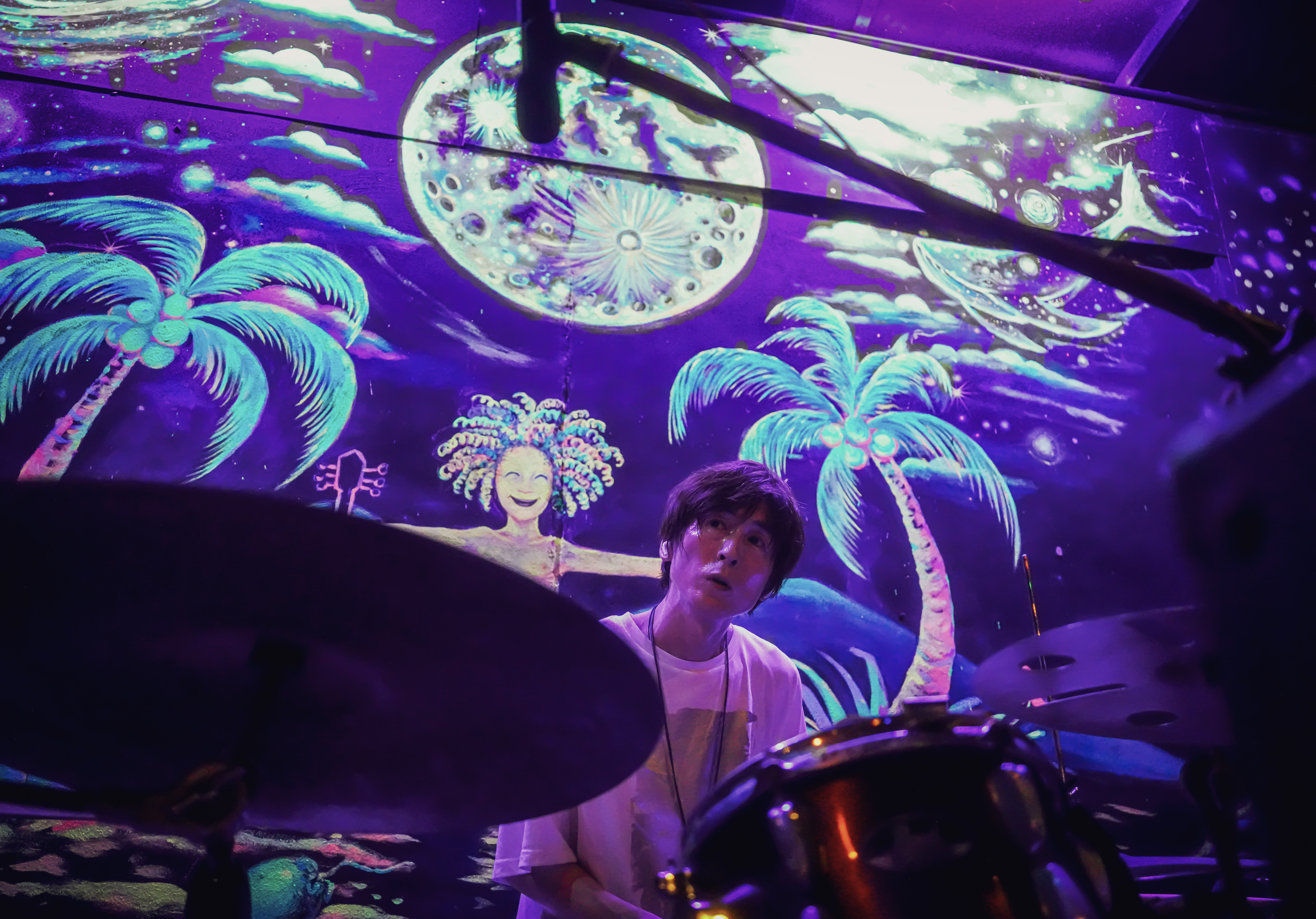 Drummer performing under vibrant stage lights.