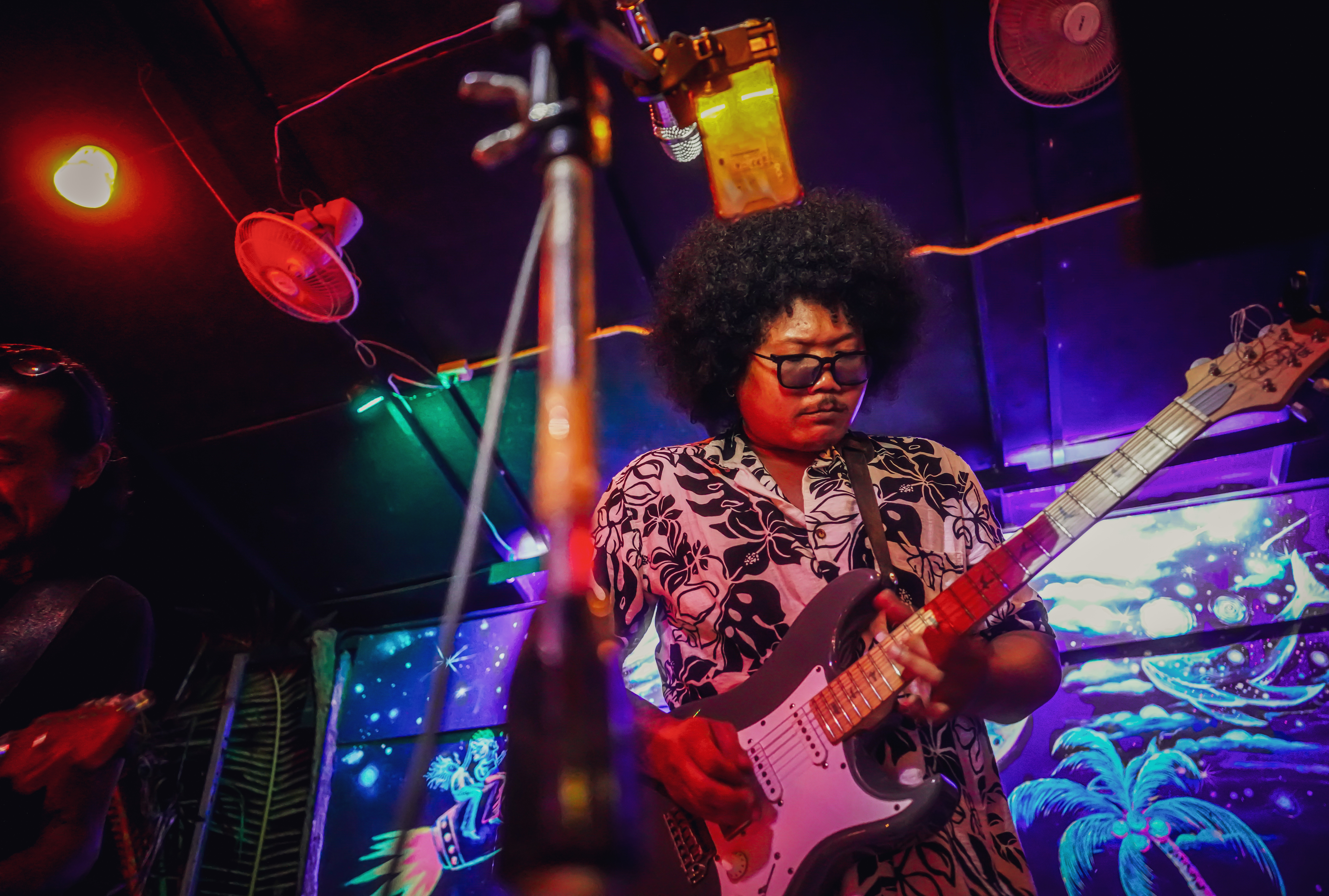 Lead singer playing guitar on stage at Rasta Home.