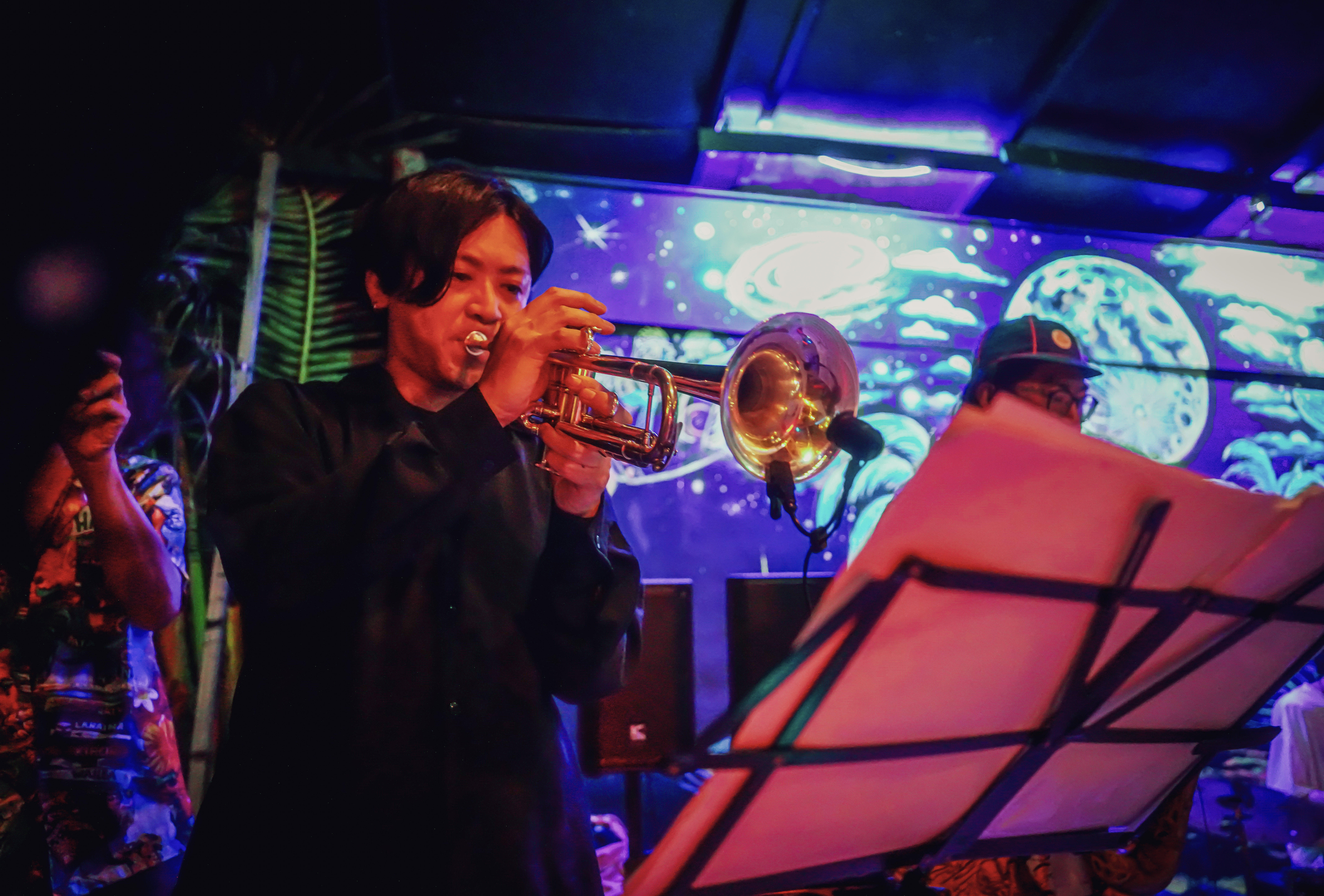 Trumpet player performing at Rasta Home with neon stage lights