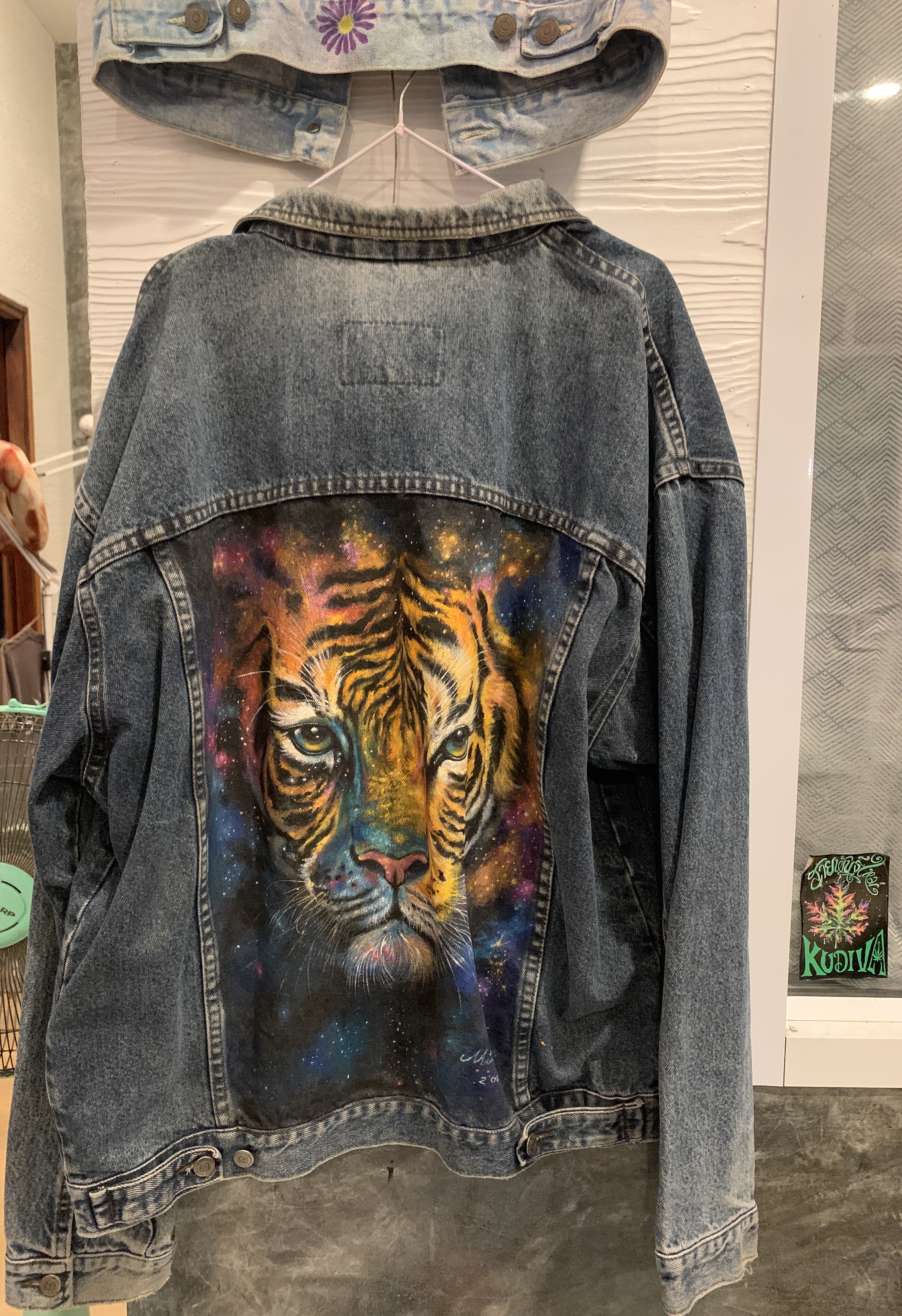 Denim jacket with a hand-painted fierce tiger design on the back.