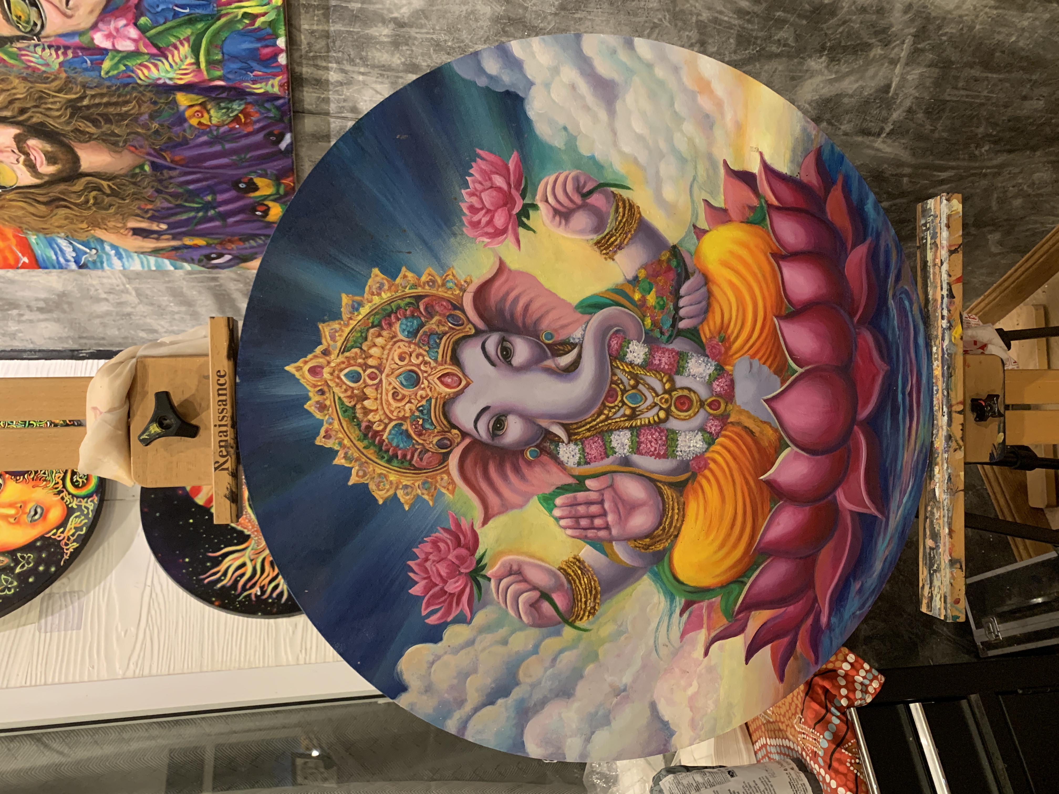 Vibrant painting of Ganesha seated on a lotus flower with radiant colors.