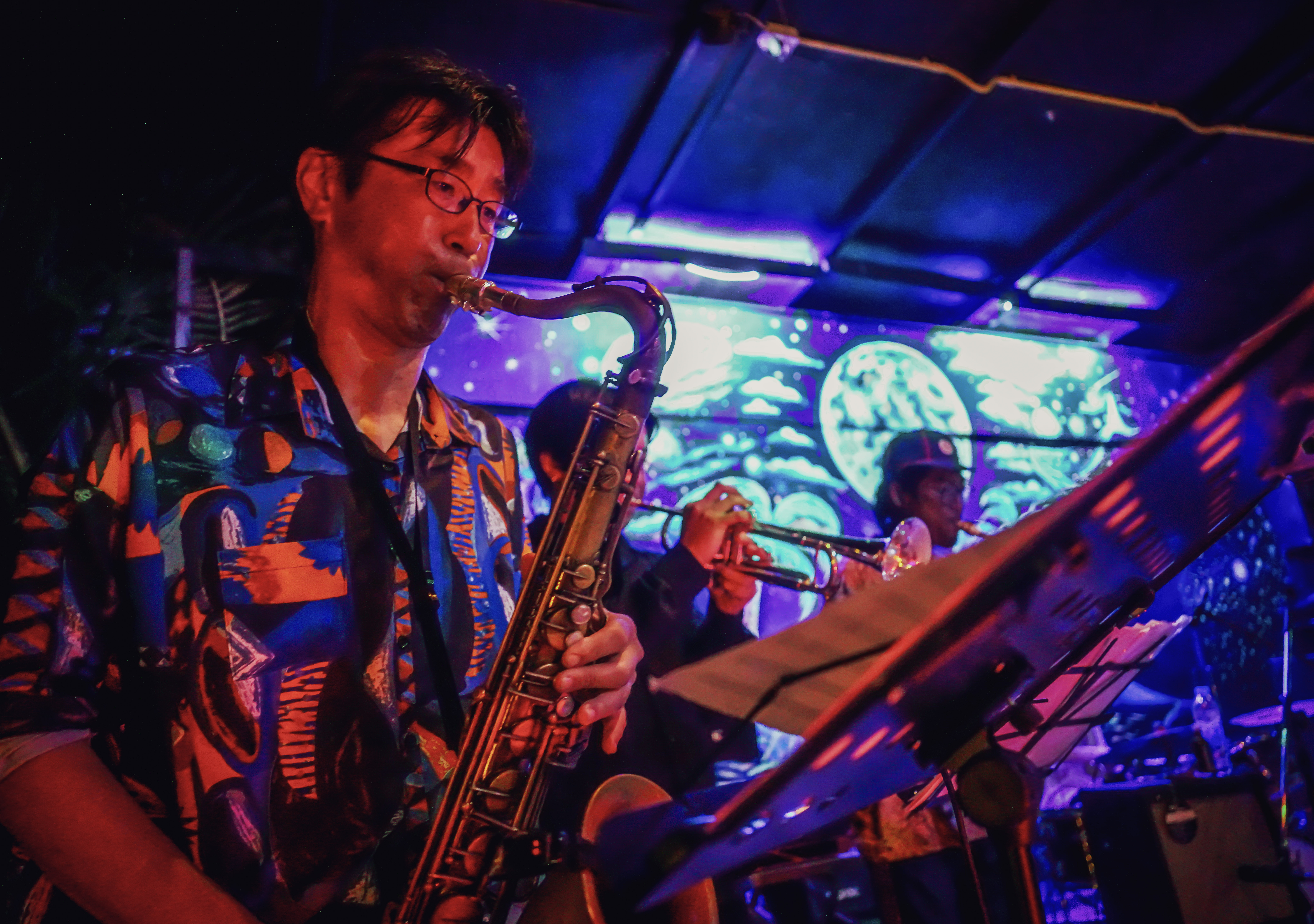 Saxophonist performing live at Rasta Home with psychedelic backdrop